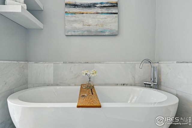 full bath featuring a freestanding tub and tile walls