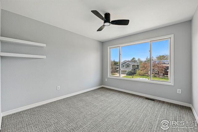 carpeted spare room with baseboards, visible vents, and ceiling fan