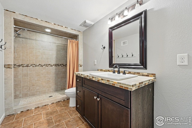 bathroom with visible vents, a stall shower, toilet, and vanity