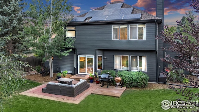 rear view of property with an outdoor living space, a chimney, a lawn, a wooden deck, and roof mounted solar panels