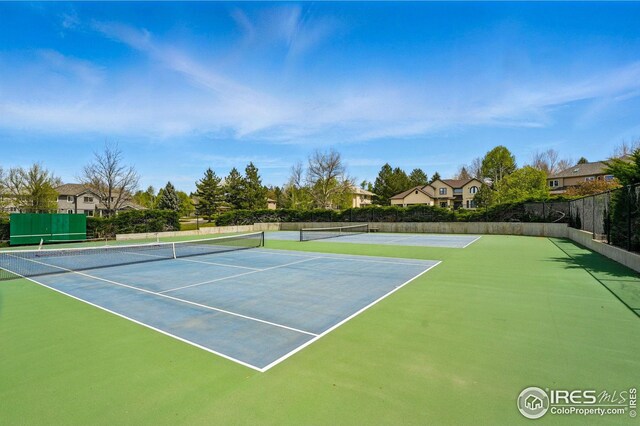 view of tennis court with community basketball court and fence