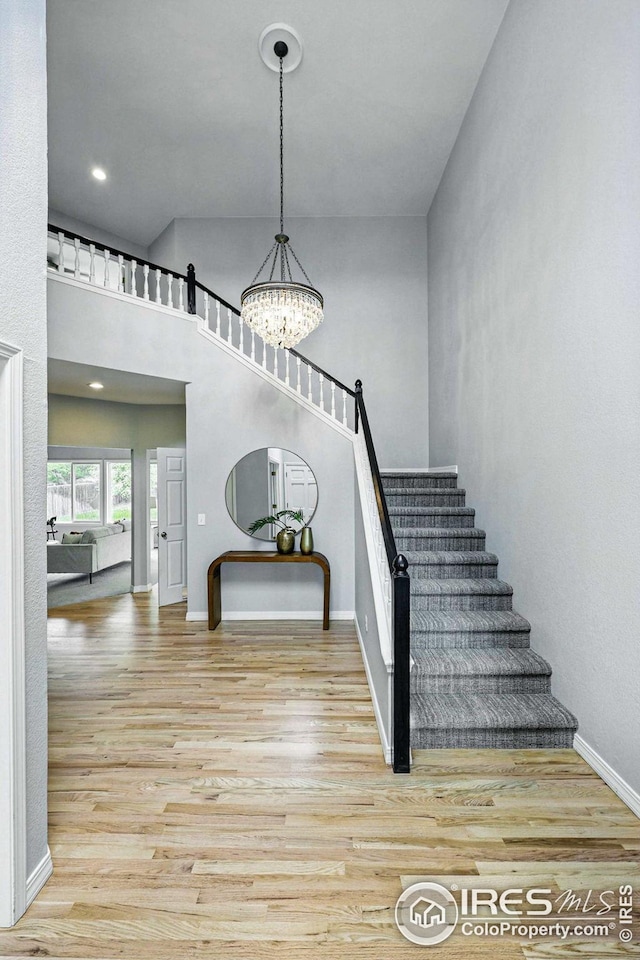 stairs featuring baseboards, wood finished floors, and a notable chandelier