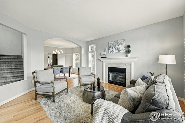 living room featuring arched walkways, baseboards, light wood finished floors, and stairs