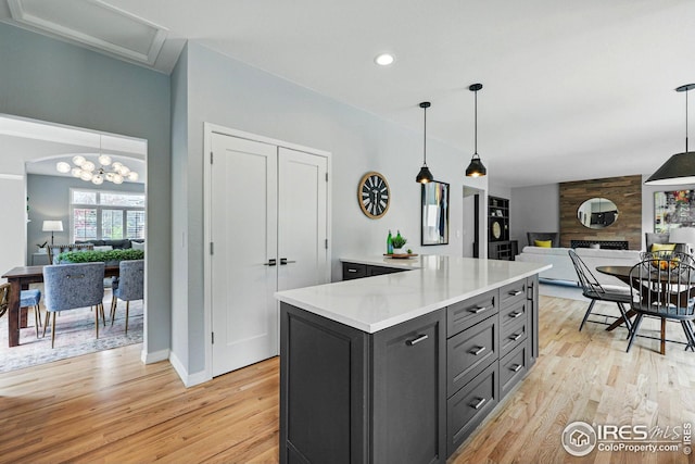 kitchen featuring light countertops, open floor plan, decorative light fixtures, and light wood-style flooring