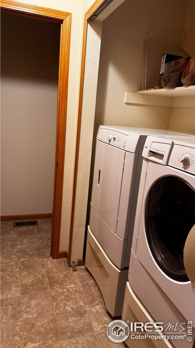clothes washing area with separate washer and dryer, laundry area, and baseboards