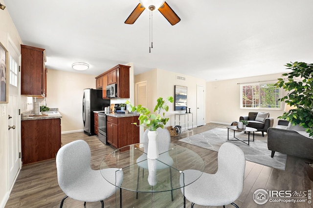 dining room with light wood-type flooring, a ceiling fan, and baseboards