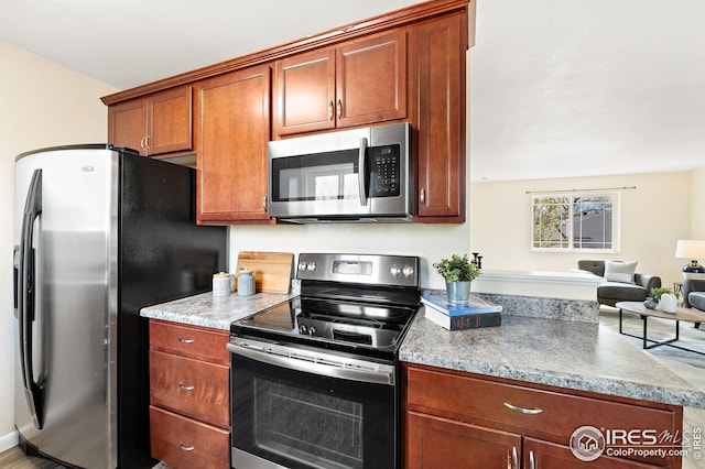 kitchen with brown cabinetry, open floor plan, and appliances with stainless steel finishes