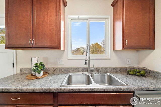 kitchen featuring a sink, dishwashing machine, and light countertops