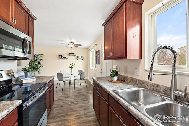 kitchen featuring ceiling fan, appliances with stainless steel finishes, a sink, and dark wood-type flooring