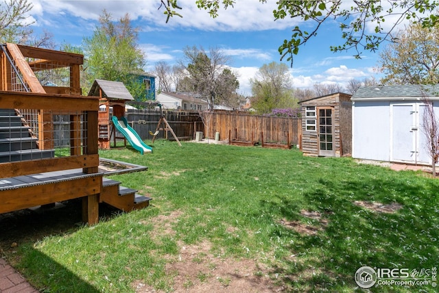 view of yard with a fenced backyard, a storage unit, an outdoor structure, and a playground