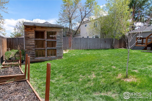 view of yard featuring a fenced backyard, a storage unit, an outdoor structure, and a garden