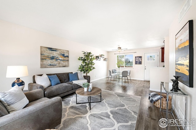 living area featuring a ceiling fan, baseboards, visible vents, and dark wood finished floors