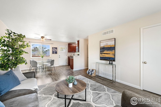 living room with baseboards, a ceiling fan, wood finished floors, and visible vents
