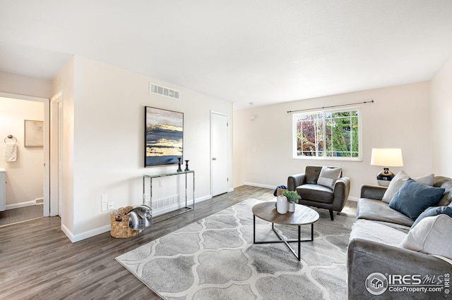 living area featuring baseboards, visible vents, and wood finished floors
