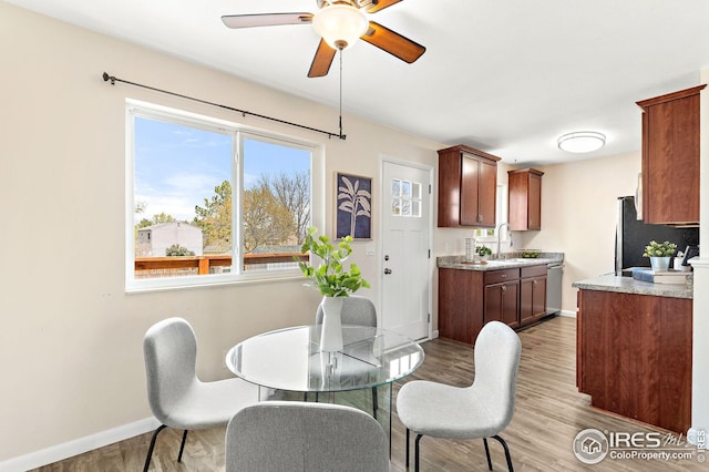 dining room with baseboards, a ceiling fan, and light wood-type flooring