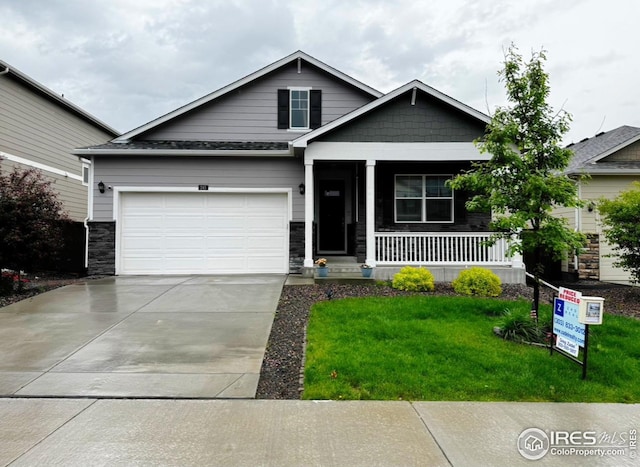 245 Swallow Rd, Johnstown, CO 80534 - view of front facade with a porch, concrete driveway, a front yard, stone siding, and an attached garage