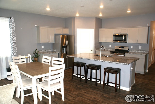 245 Swallow Rd, Johnstown, CO 80534 - kitchen with stainless steel appliances, a sink, dark wood finished floors, a center island with sink, and recessed lighting
