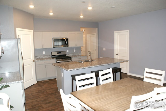 245 Swallow Rd, Johnstown, CO 80534 - kitchen featuring appliances with stainless steel finishes, a sink, dark wood finished floors, an island with sink, and white cabinets