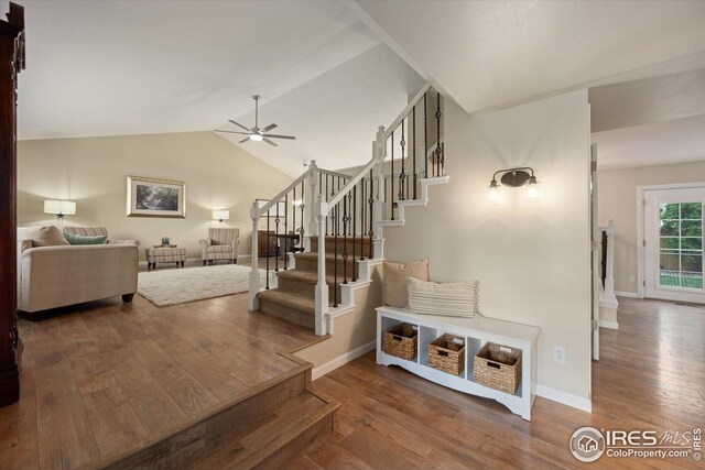 stairway with baseboards, a ceiling fan, lofted ceiling, and hardwood / wood-style floors