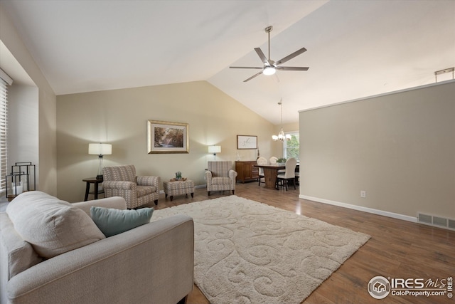 living area with visible vents, vaulted ceiling, wood finished floors, baseboards, and ceiling fan with notable chandelier