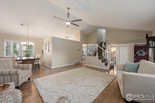 living room featuring visible vents, stairs, wood finished floors, baseboards, and ceiling fan with notable chandelier