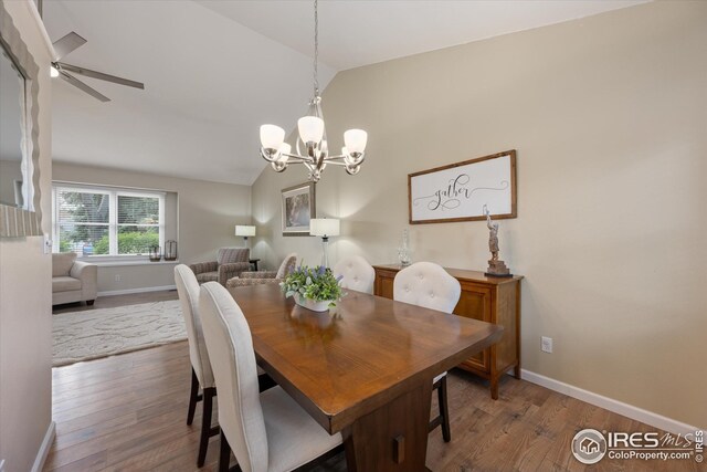 dining area with baseboards, wood finished floors, lofted ceiling, and ceiling fan with notable chandelier