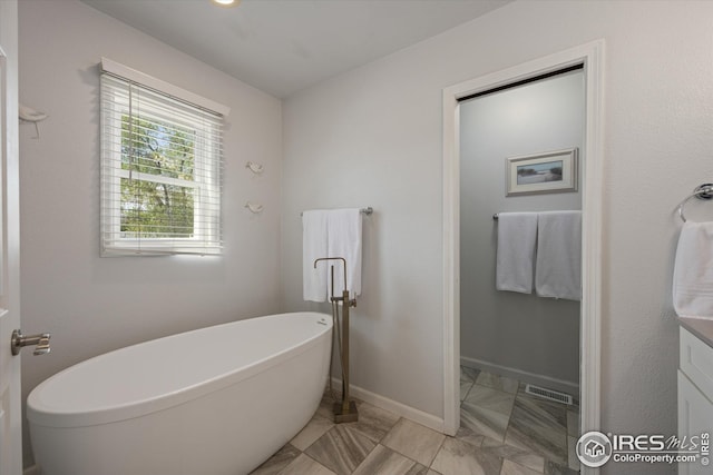 bathroom featuring a freestanding tub, visible vents, baseboards, and marble finish floor