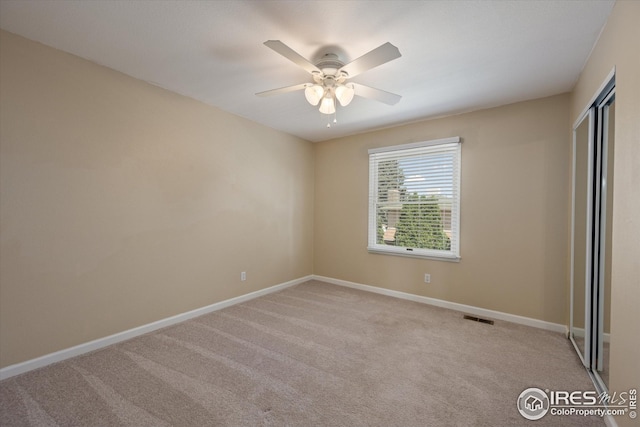 carpeted spare room with baseboards, ceiling fan, and visible vents