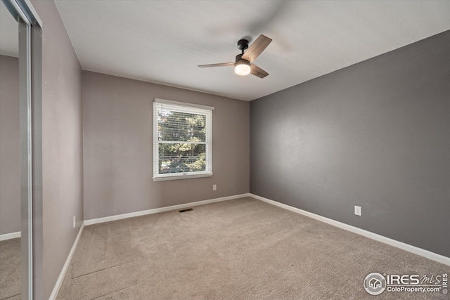 spare room with visible vents, carpet flooring, baseboards, and ceiling fan