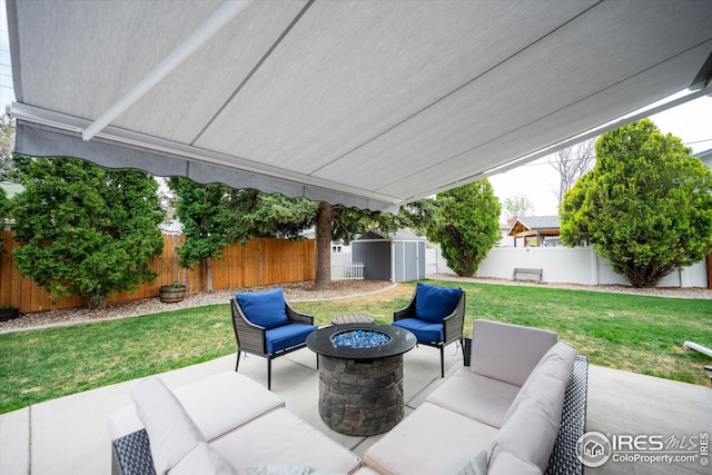 view of patio featuring a fenced backyard, an outdoor living space with a fire pit, an outbuilding, and a shed