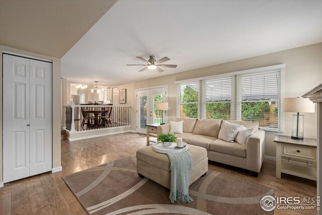 living area featuring baseboards, hardwood / wood-style flooring, and ceiling fan with notable chandelier