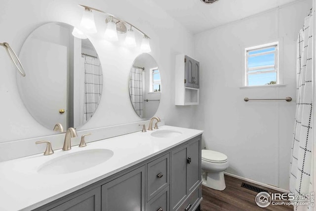 full bathroom with visible vents, a sink, wood finished floors, and toilet