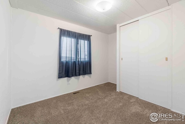 unfurnished bedroom with carpet floors, visible vents, and a closet