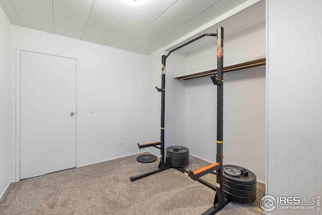 exercise room featuring carpet floors, a textured ceiling, and baseboards