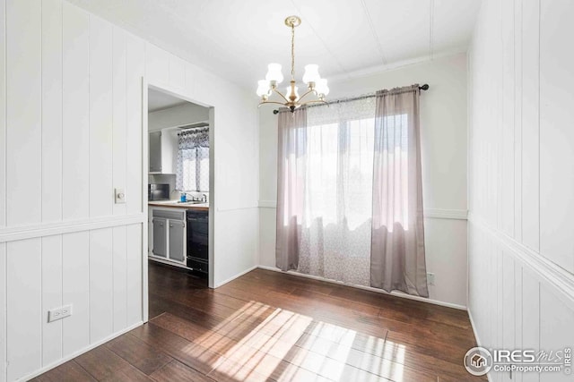 unfurnished dining area featuring an inviting chandelier, a sink, and dark wood-style floors