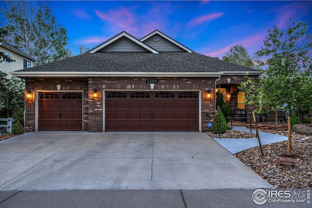 single story home with a garage, a shingled roof, concrete driveway, and brick siding