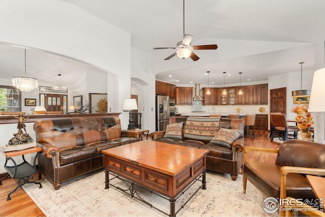 living area with arched walkways, ceiling fan, recessed lighting, and light wood-style floors