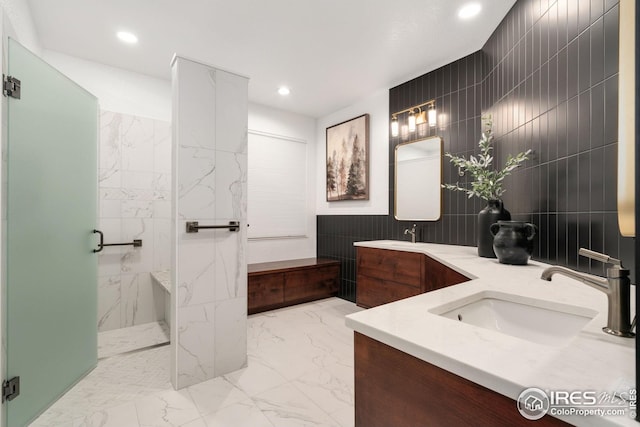 full bathroom with double vanity, tile walls, a sink, a walk in shower, and recessed lighting