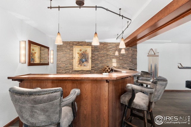bar with hanging light fixtures, bar, baseboards, and wood finished floors