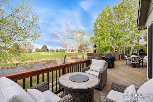wooden deck featuring outdoor dining space, a water view, and a grill
