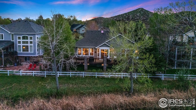 rear view of property featuring a deck with mountain view and a fenced backyard