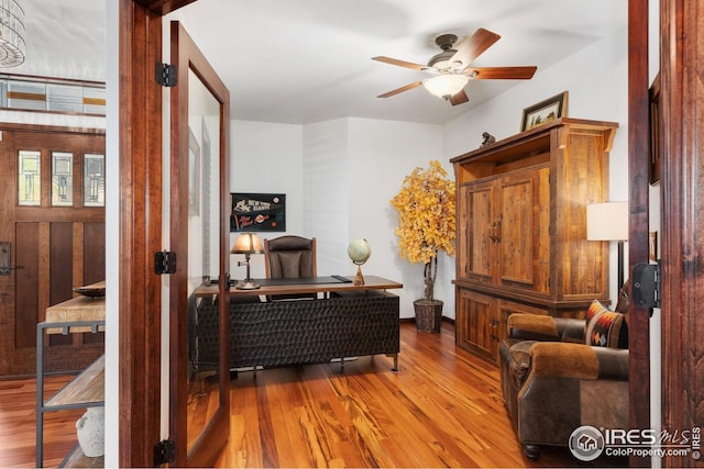 sitting room with baseboards, a ceiling fan, and wood finished floors
