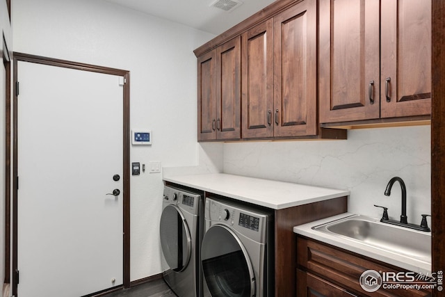 laundry area featuring cabinet space, separate washer and dryer, visible vents, and a sink