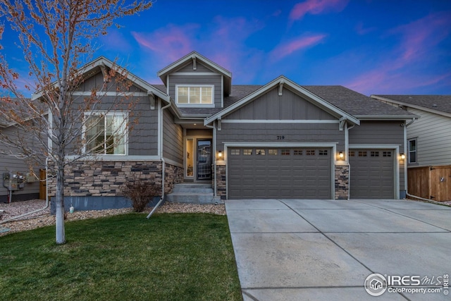 craftsman house with a lawn, a garage, driveway, and stone siding
