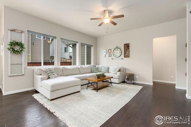 living area featuring dark wood-style flooring, ceiling fan, and baseboards