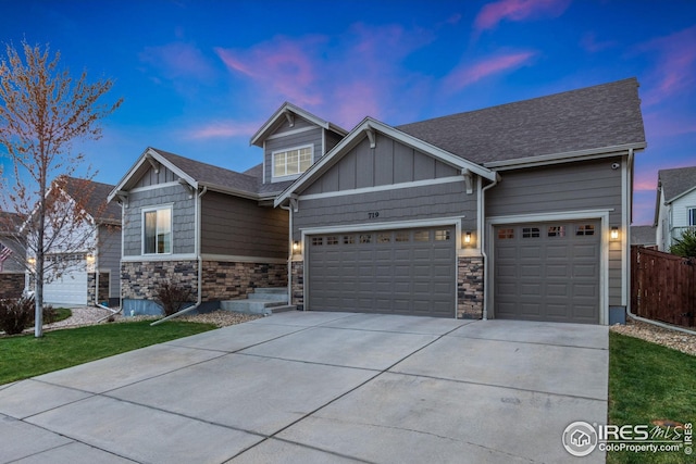 craftsman-style home featuring fence, stone siding, a garage, board and batten siding, and driveway