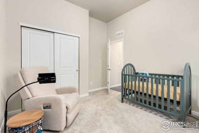 carpeted bedroom with baseboards, a closet, a nursery area, and visible vents