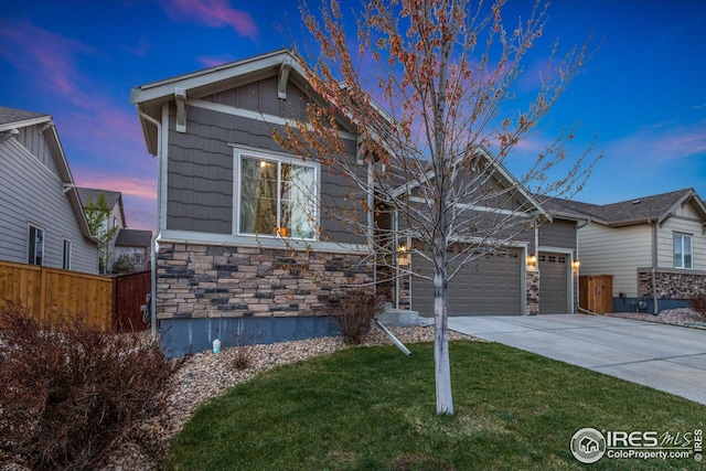 craftsman house featuring fence, an attached garage, driveway, and stone siding