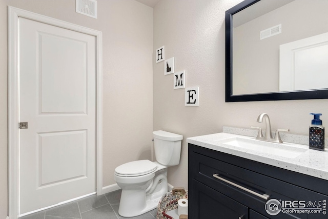 half bath with visible vents, tile patterned floors, toilet, and vanity