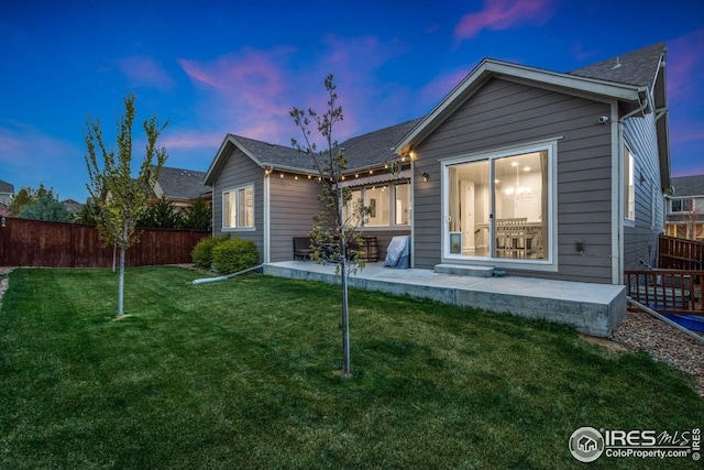 rear view of house with a lawn, a patio, and fence